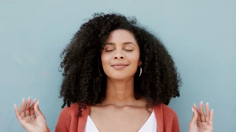 Woman with curly hair and eyes closed, relaxing calmly