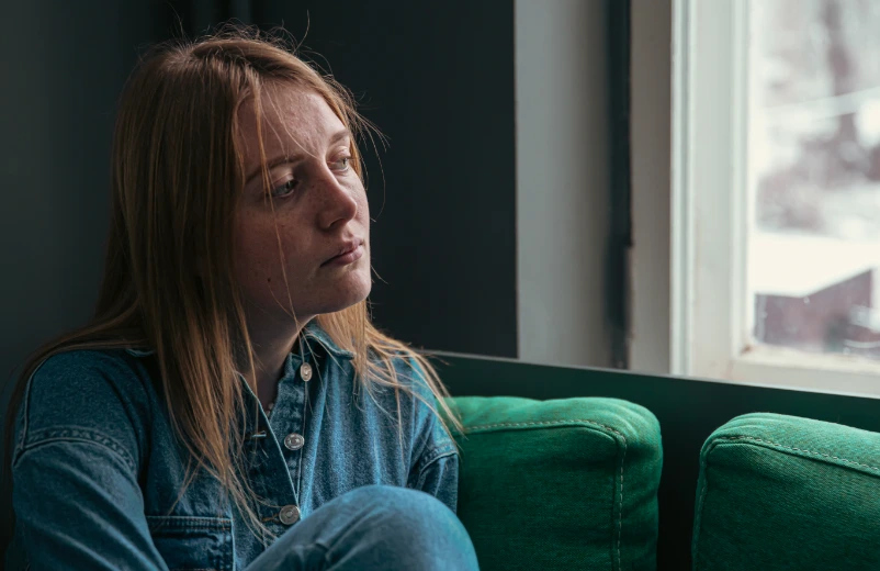 Woman sitting by a window experiencing depression and anxiety, seeking support at Harmony Health and Psychiatry