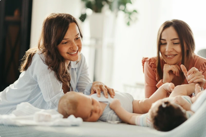 Happy mother smiling and holding her newborn baby in natural light, thriving after postpartum depression care