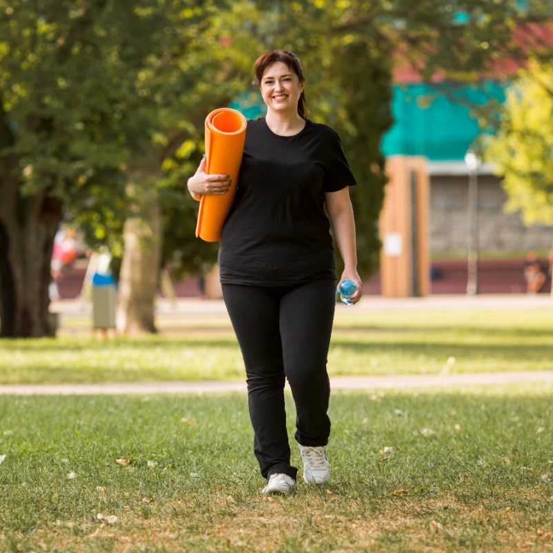 Woman in sportswear holding a yoga mat, starting her weight loss therapy journey with Harmony Health and Psychiatry