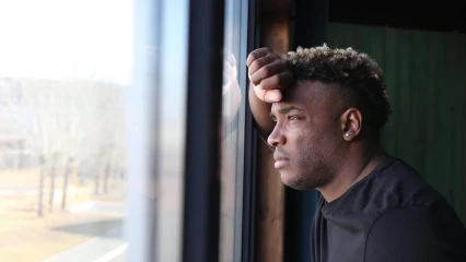 Black man looking thoughtfully out of a window