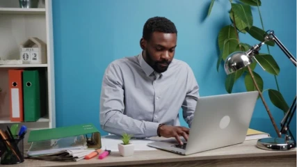 Black man working at a laptop, representing adult ADHD focus and attention challenges