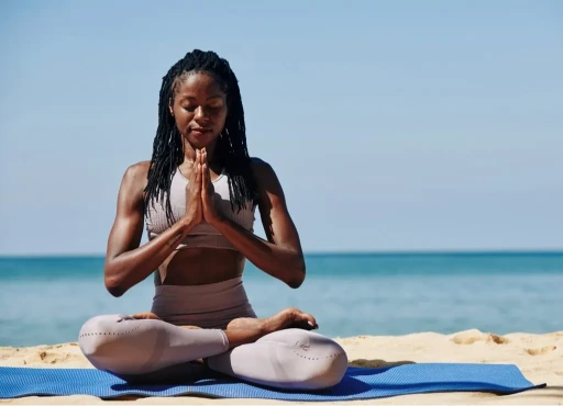Black woman practicing yoga and meditation on the beach